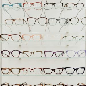 Stylish rims with lenses for vision arranged on glass shelves in ophthalmology salon